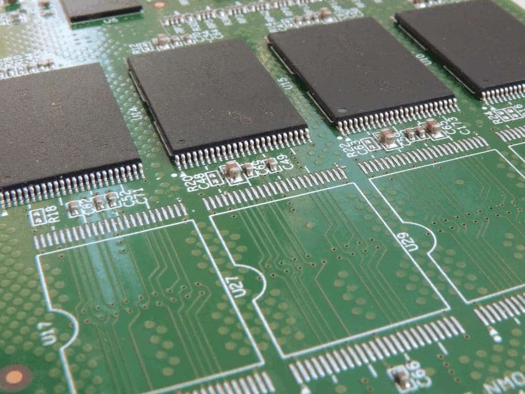 Close-up of a printed circuit board showing IC footprints, silkscreen outlines, and reference designators